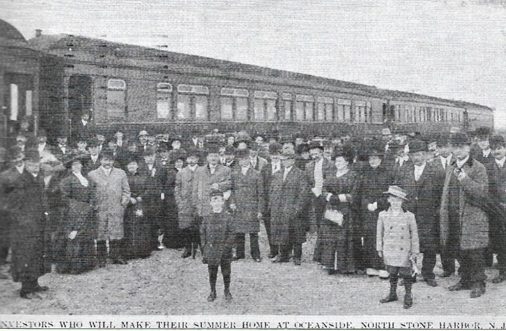 Early postcard showing a large group of formally dressed men, women, and children standing beside Pennsylvania Railroad passenger cars, captioned "INVESTORS WHO WILL MAKE THEIR SUMMER HOME AT OCEANSIDE, NORTH STONE HARBOR, N. J."